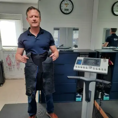 Client getting fitted for his EMS suit beside the miha bodytec machine