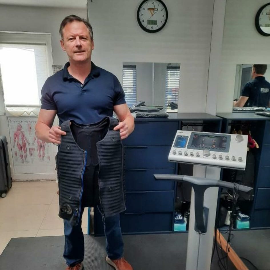 Your trainer in the Total Body TEC studio in Leixlip, holding a miha bodytec training vest beside the control unit